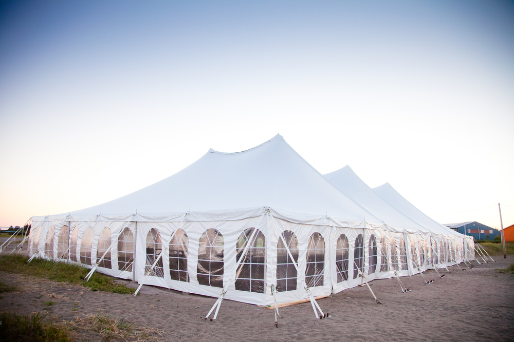 a white event tent with sidewalls and stakes in the ground