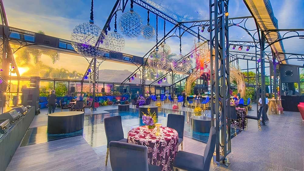 The interior of the large garden tent with an array of tables and chairs with colorful light pieces and spherical chandeliers.