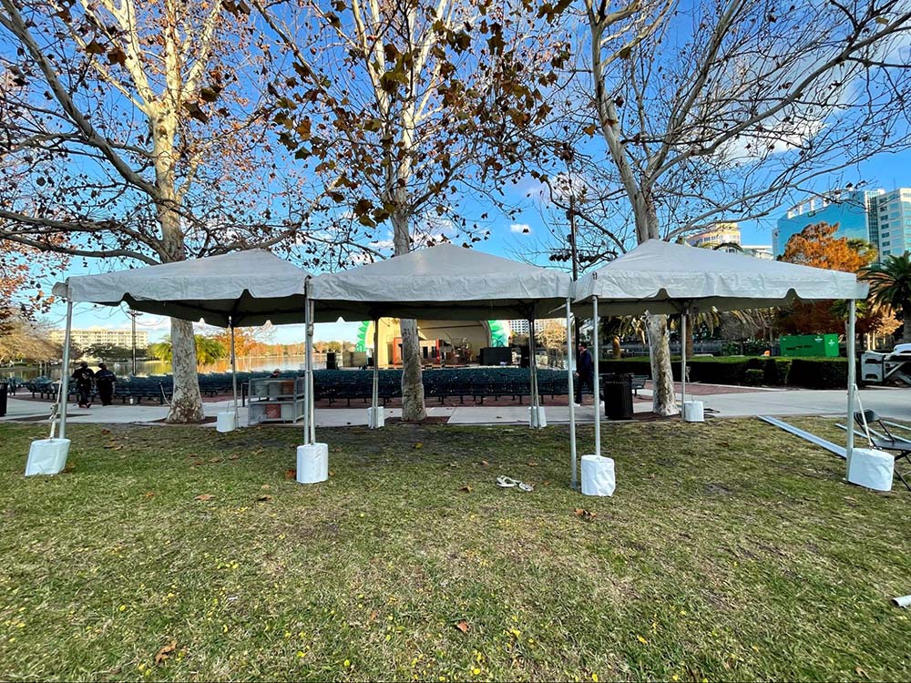 Three white tents stationed behind rows of chairs in front of a theater.