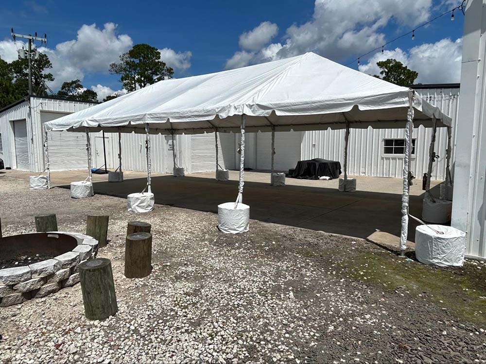 A large outdoor tent set up next to an outdoor firepit with log seats