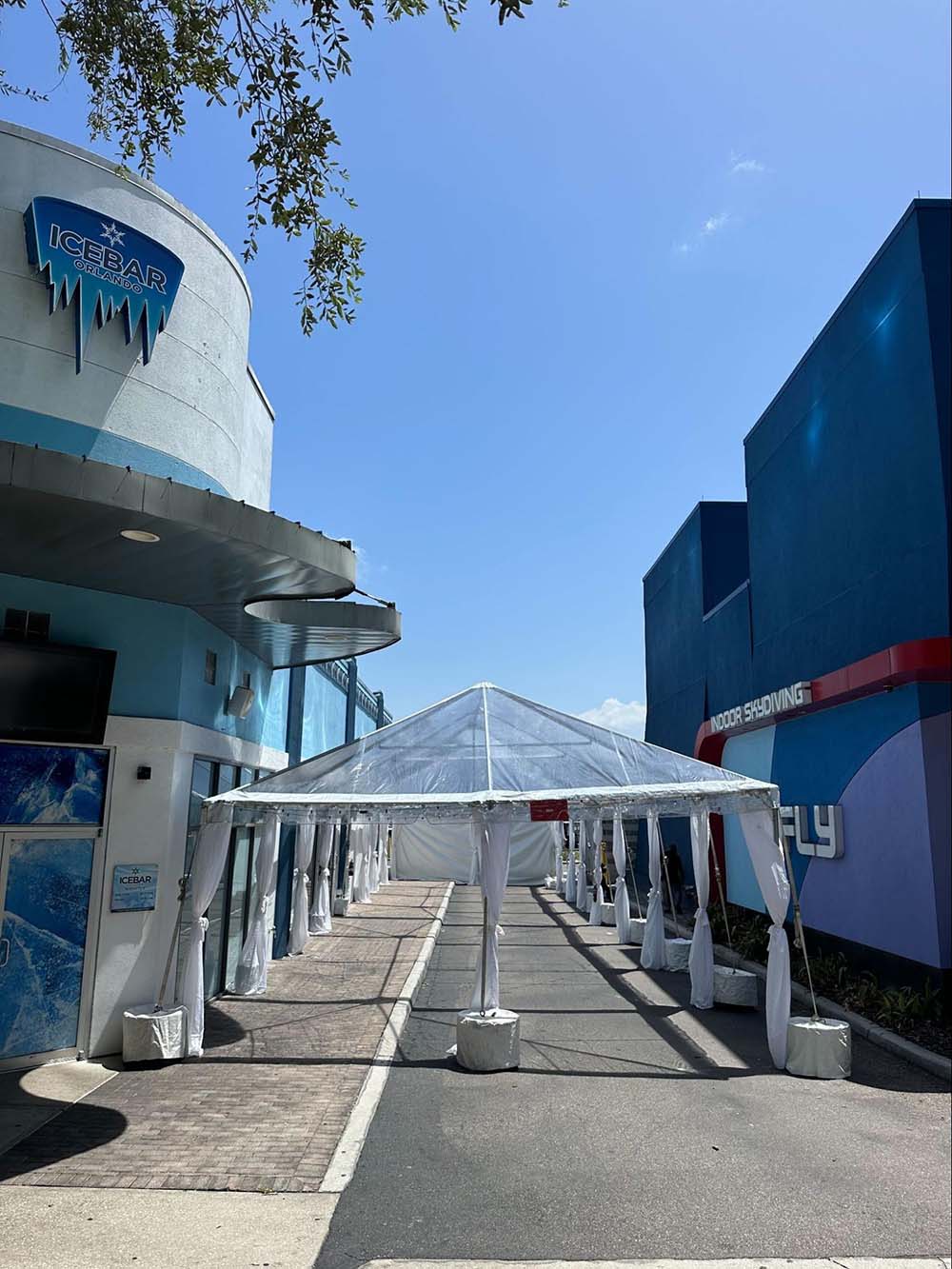 A long, outdoor garden tent with a transparent top outside of ICEBAR